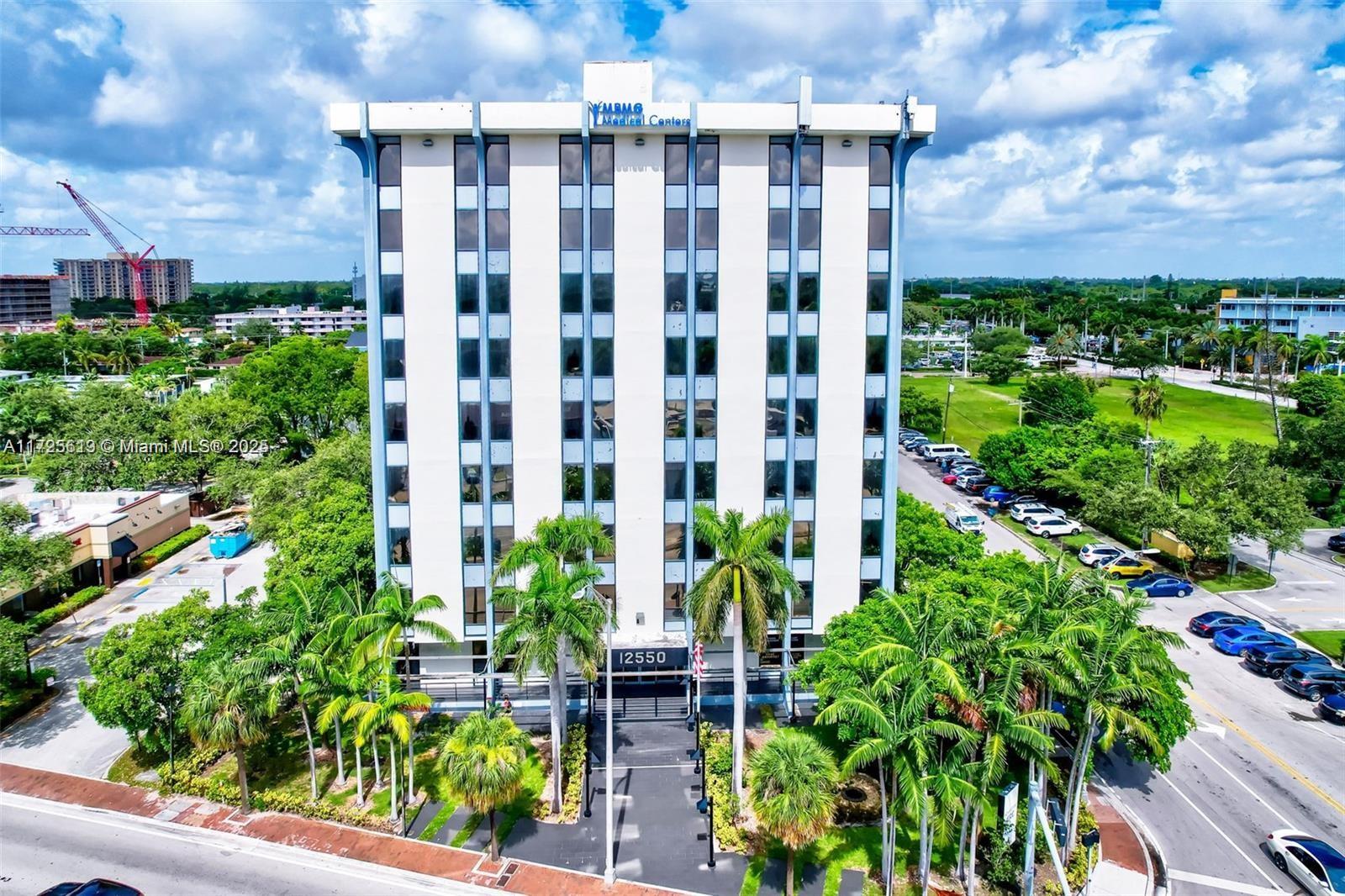 An aerial view of a multi-story office building surrounded by palm trees and parking lots — 12550 Biscayne Blvd # 4, North Miami FL 33181, NORTH MIAMI, FL