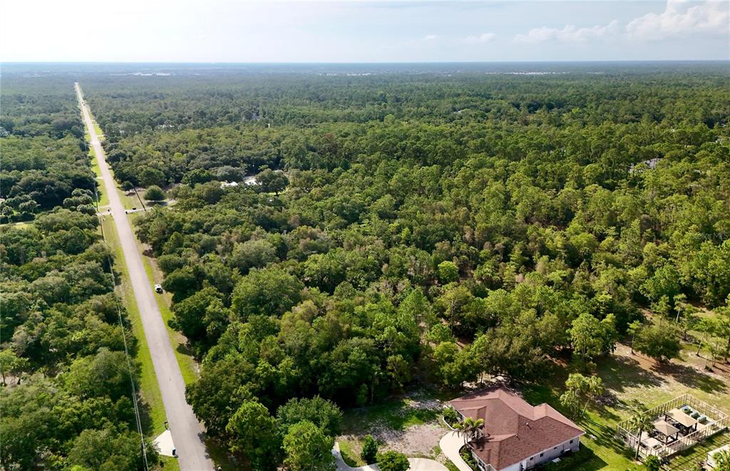 An aerial view shows a house with a brown roof next to a long road — 280 35TH AVENUE NW, NAPLES, FL