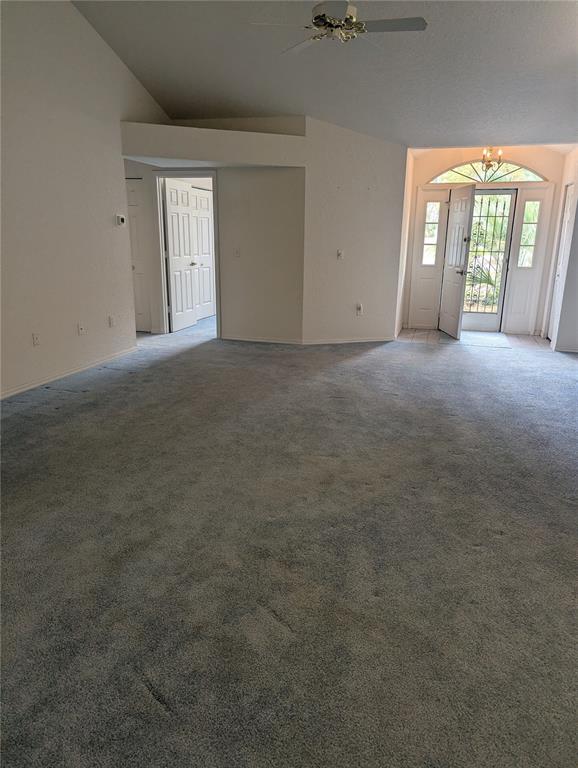 A spacious living room with gray carpet, vaulted ceilings, and an open front entryway — 10816 SW 83RD AVENUE, OCALA, FL