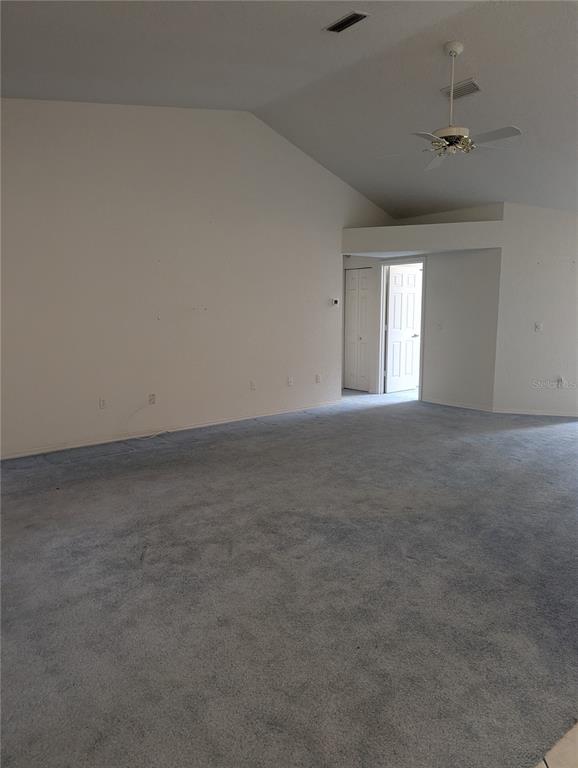 A spacious room with vaulted ceilings, gray carpeting, and a ceiling fan — 10816 SW 83RD AVENUE, OCALA, FL