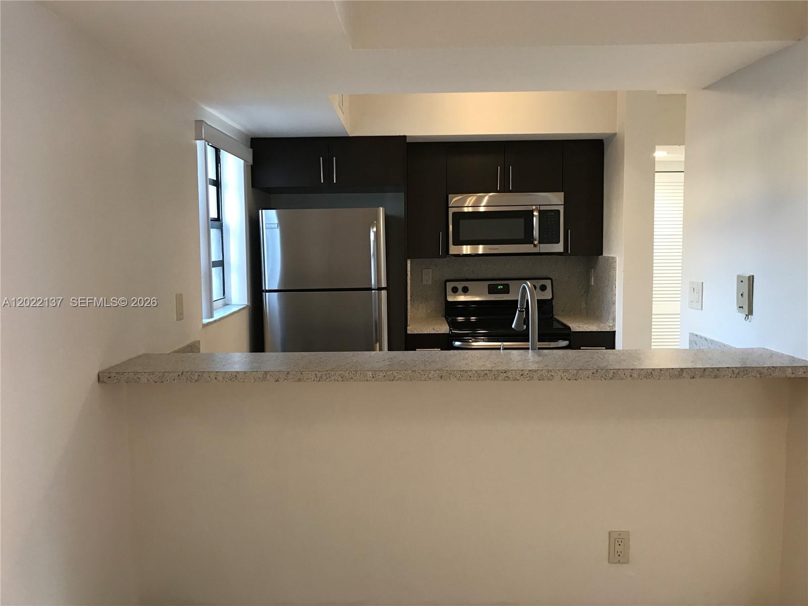 A kitchen features dark wood cabinets, stainless steel appliances, and a granite breakfast bar — 18224 Mediterranean Blvd # 17, Miami FL 33015, MIAMI, FL