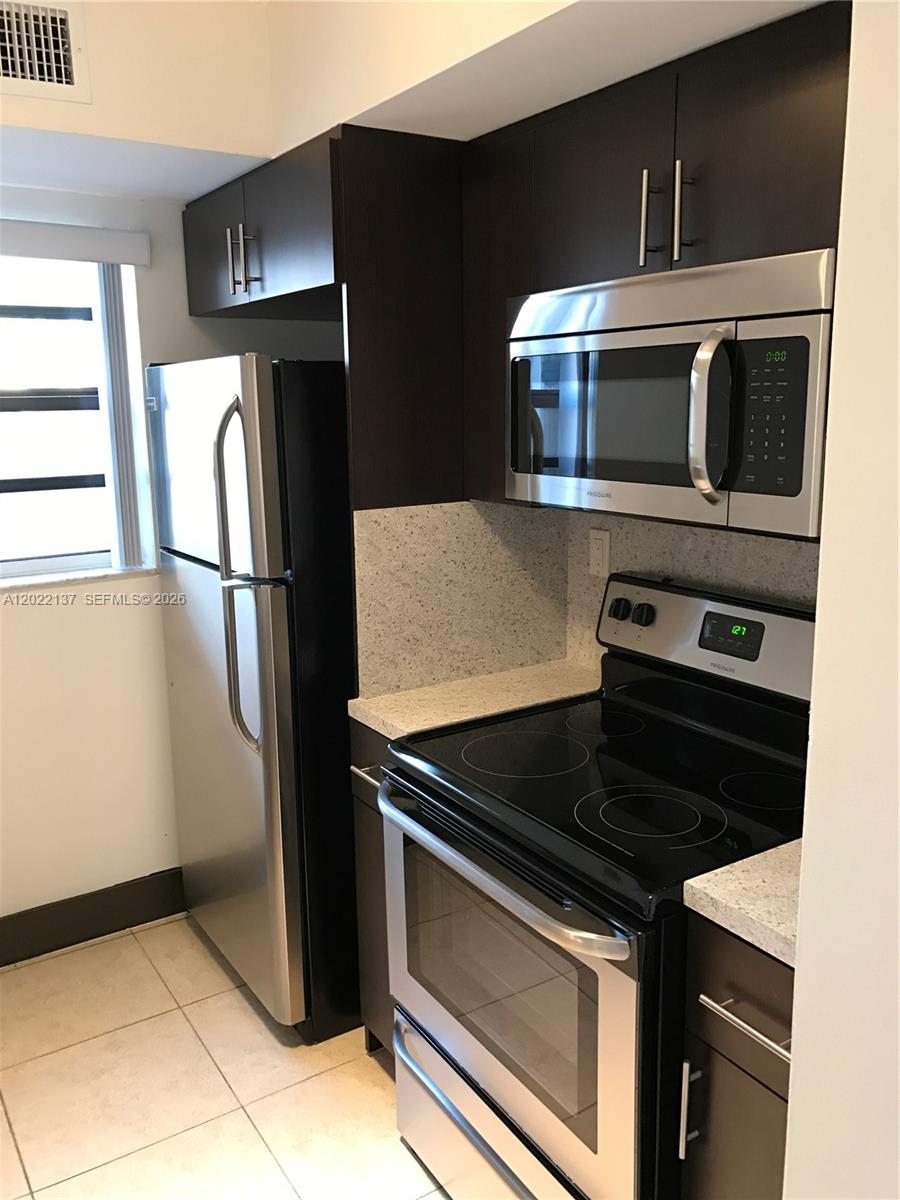 A kitchen features dark wood cabinets, stainless steel appliances, and light-colored speckled countertops — 18224 Mediterranean Blvd # 17, Miami FL 33015, MIAMI, FL