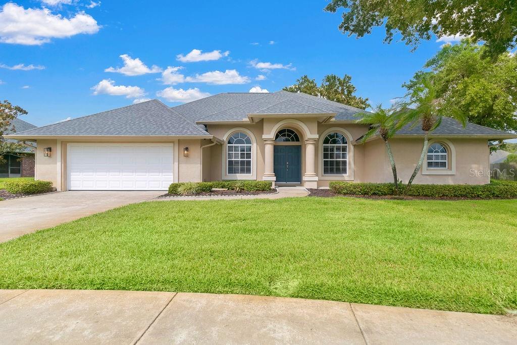 A single-story suburban house with a two-car garage, arched windows, and a manicured lawn — 1525 DATE DRIVE DRIVE, TITUSVILLE, FL