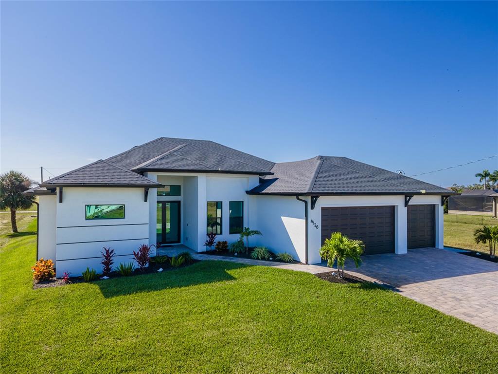 A modern single-story house with a white exterior, dark roof, and a two-car garage — 4126 NW 39TH STREET, CAPE CORAL, FL