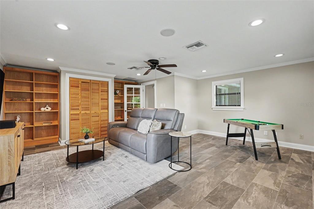 A living room features a grey reclining sofa, a television on a wooden console, and tile flooring — 475 HOLLY HILL ROAD, OLDSMAR, FL