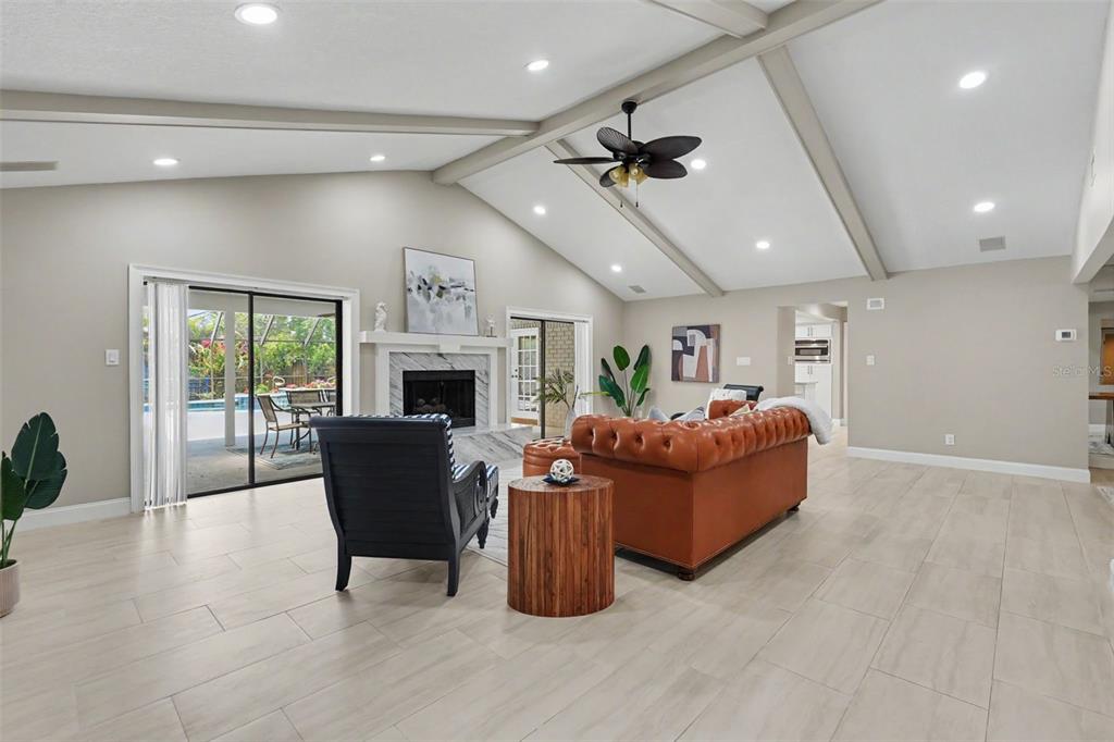 A living room features a vaulted ceiling, a leather sofa, and a fireplace with doors — 475 HOLLY HILL ROAD, OLDSMAR, FL