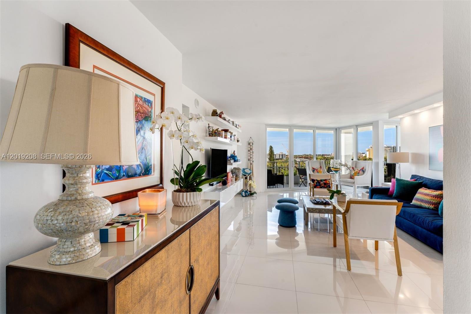 A bright living room features white tile floors, a blue sofa, and floor-to-ceiling windows — 1000 Quayside Ter # 901, Miami FL 33138, MIAMI, FL
