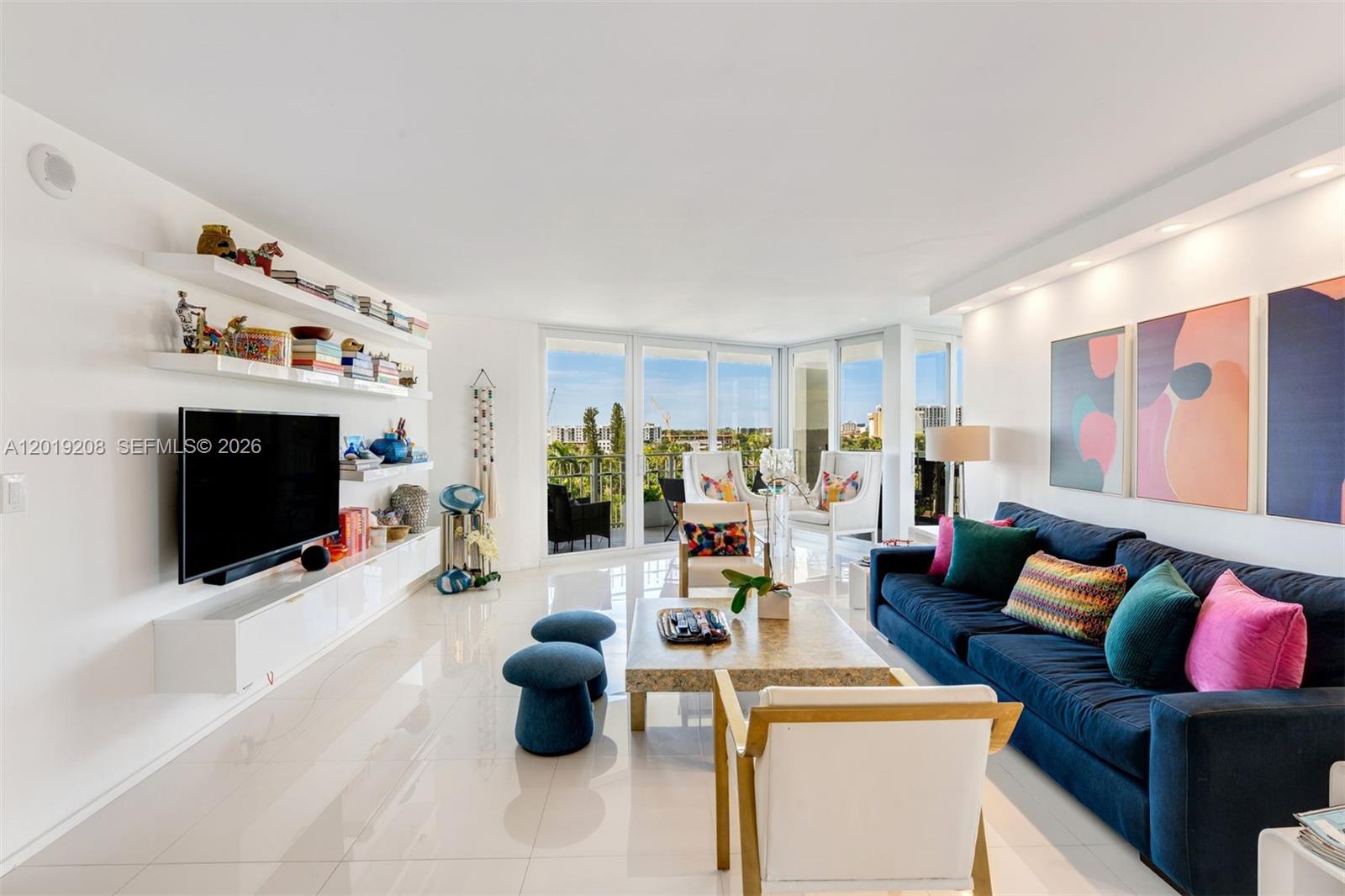A bright living room features white tile floors, a blue sofa, and a wall-mounted television — 1000 Quayside Ter # 901, Miami FL 33138, MIAMI, FL