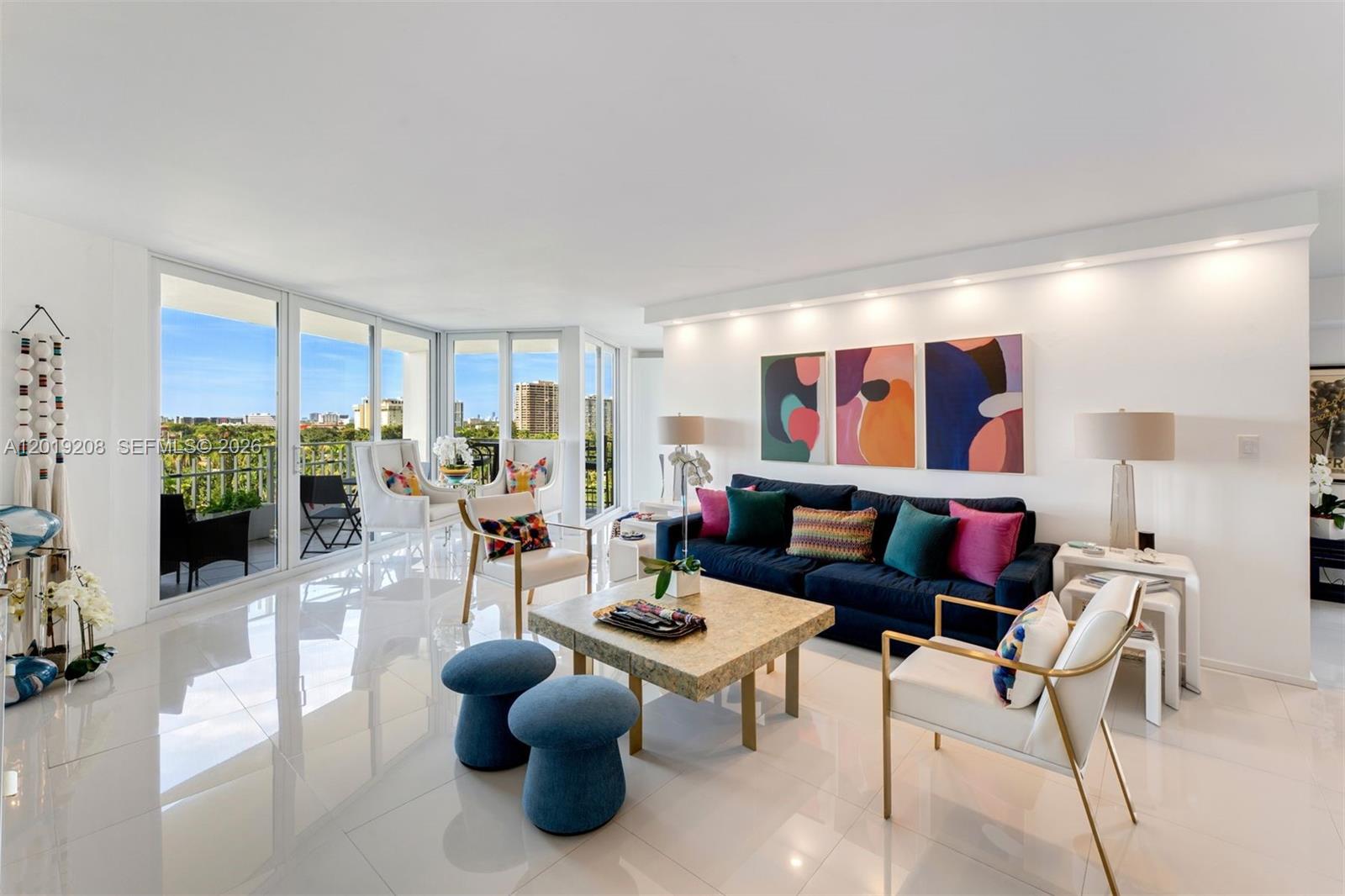 A bright living room features a navy sofa, white armchairs, and a stone coffee table — 1000 Quayside Ter # 901, Miami FL 33138, MIAMI, FL