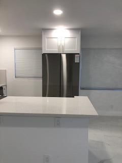 A modern kitchen features a stainless steel refrigerator, white cabinetry, and a white quartz island — 392 Mansfield I, Boca Raton FL 33434, BOCA RATON, FL
