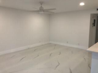 An empty room with white walls, a ceiling fan, and light-colored marble-patterned tile flooring — 392 Mansfield I, Boca Raton FL 33434, BOCA RATON, FL