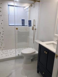A modern bathroom features a glass-enclosed walk-in shower, a white toilet, and a navy vanity — 392 Mansfield I, Boca Raton FL 33434, BOCA RATON, FL