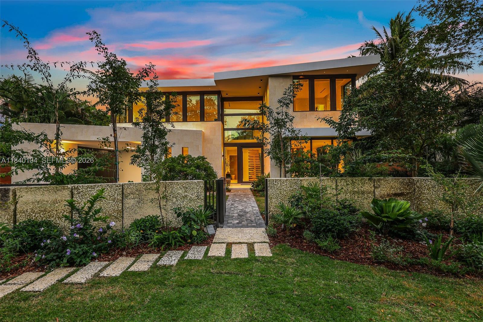 A modern two-story house with a stone wall, landscaped yard, and a paved walkway entrance — 3860 Little Ave, Miami FL 33133, MIAMI, FL