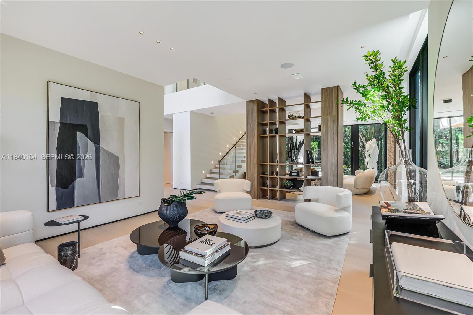 A modern living room features a large abstract painting, wooden shelving, and white armchairs — 3860 Little Ave, Miami FL 33133, MIAMI, FL