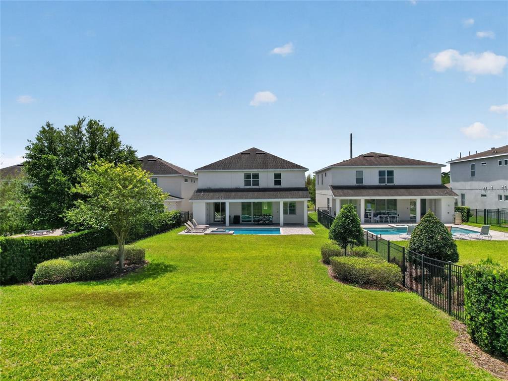 The backyard features a swimming pool, a covered patio, and a lawn between two houses — 7450 MARKER AVENUE, KISSIMMEE, FL