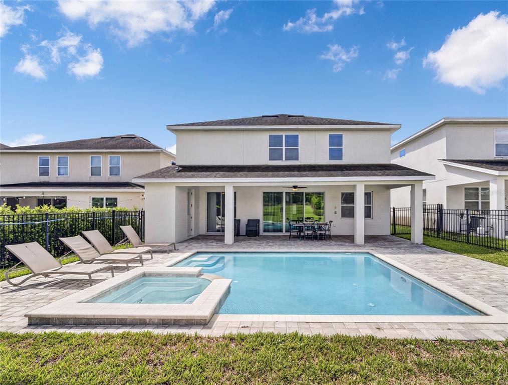 A two-story house exterior features a covered patio, a swimming pool, and a hot tub — 7450 MARKER AVENUE, KISSIMMEE, FL