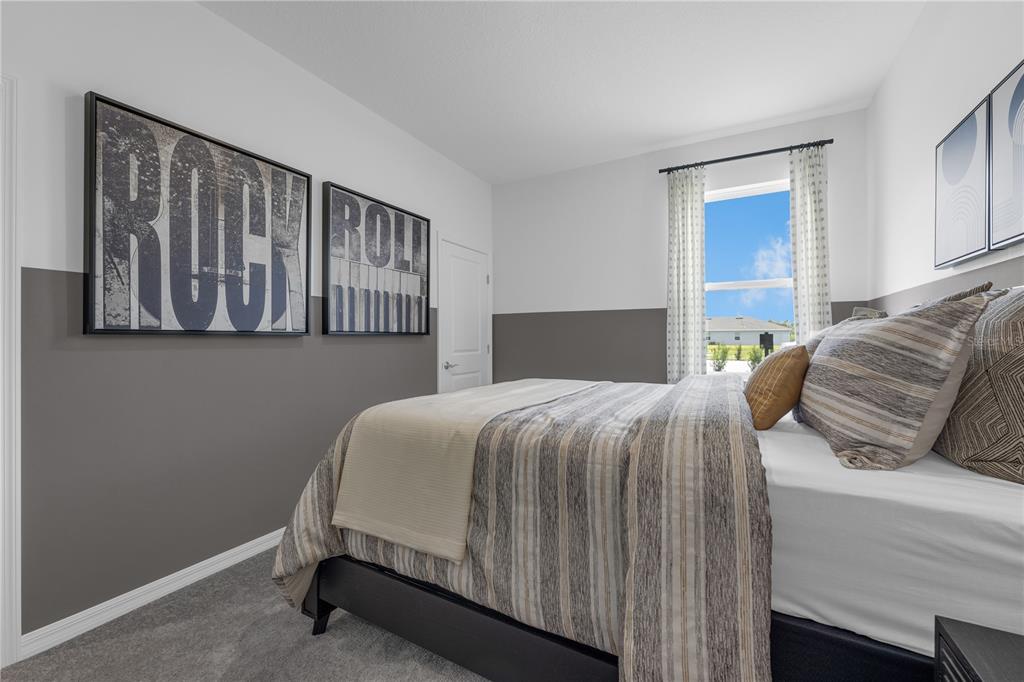 A bedroom features gray and white walls, a striped bedspread, and rock-themed wall art — 1817 AMERICAN WAY, HAINES CITY, FL