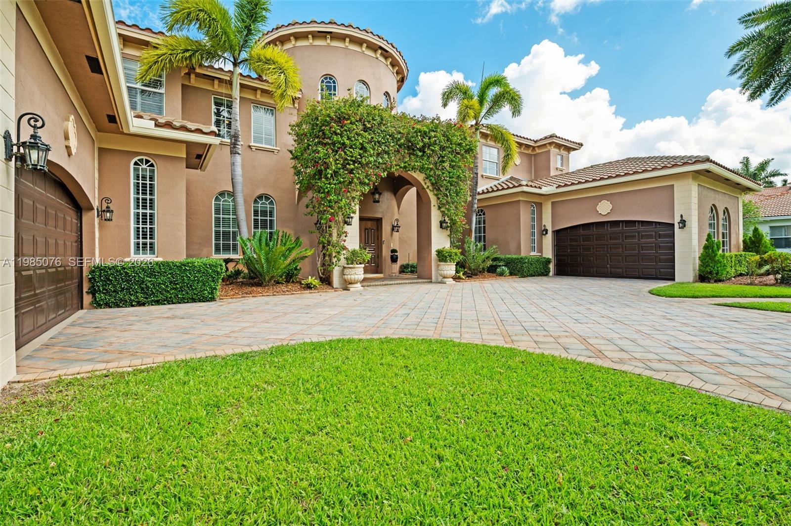 A two-story Mediterranean-style house features a paved driveway, a three-car garage, and lush landscaping — 12821 Kapok Ln, Davie FL 33330, DAVIE, FL