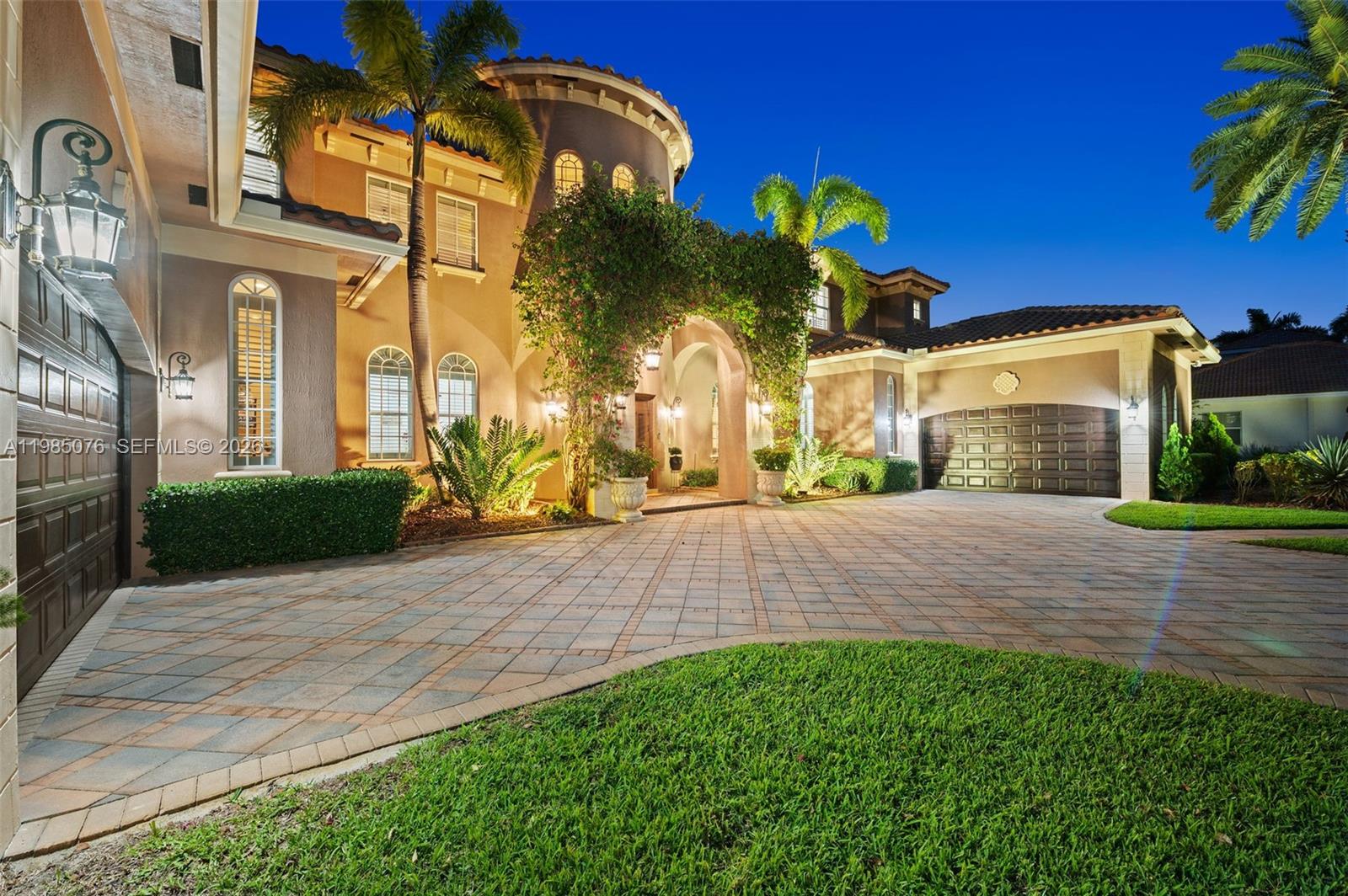 A two-story Mediterranean-style house features a paved driveway, arched entryway, and palm trees at dusk — 12821 Kapok Ln, Davie FL 33330, DAVIE, FL