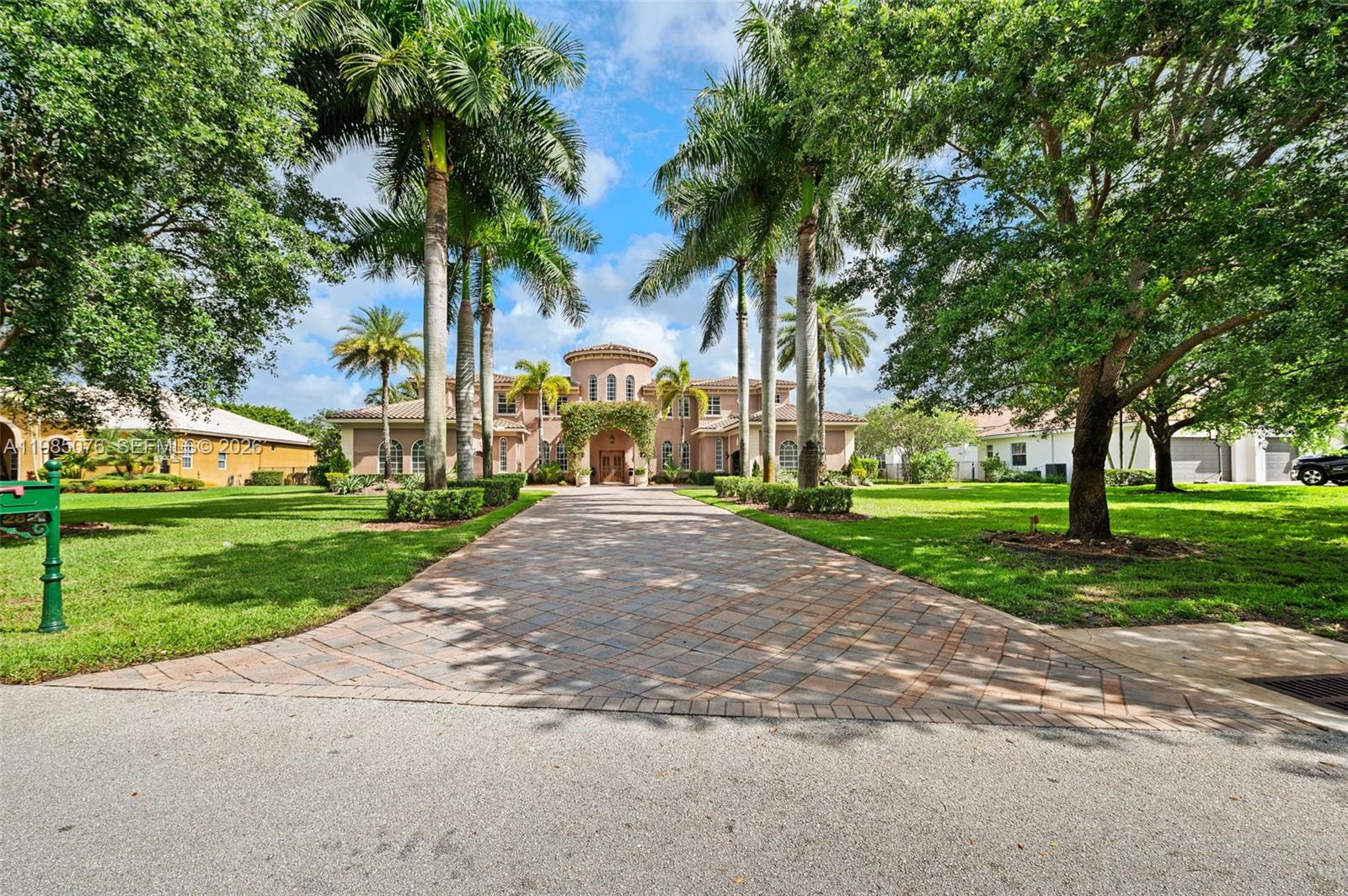 A large two-story Mediterranean-style house features a long paved driveway lined with tall palm trees — 12821 Kapok Ln, Davie FL 33330, DAVIE, FL