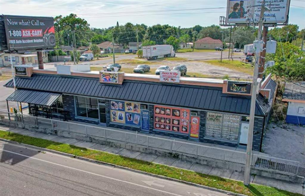 An aerial view of a single-story commercial building with a dark metal roof and signage — 9002 N 40TH ST, TAMPA, FL