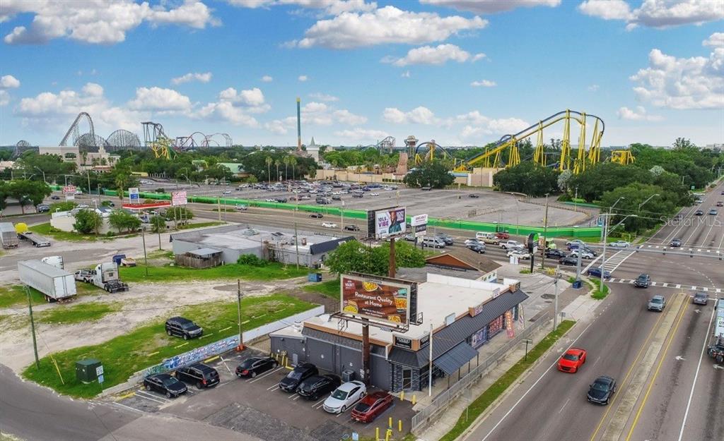 An aerial view shows a commercial building with a parking lot near a large theme park — 9002 N 40TH ST, TAMPA, FL
