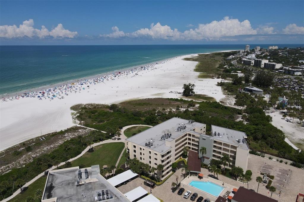 An aerial view of a beachfront condominium complex with a pool and white sand beach — 5740 MIDNIGHT PASS ROAD UNIT 303F, SARASOTA, FL