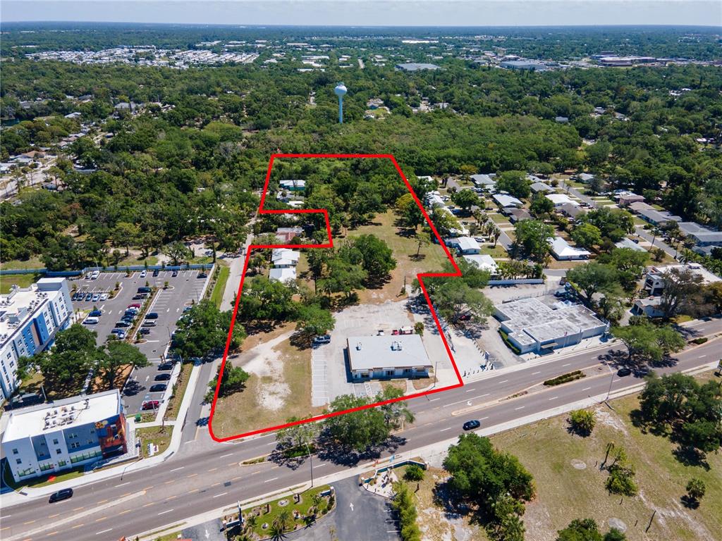 An aerial view shows a commercial building and several houses outlined in red on land — 4500 N TAMIAMI TRAIL, SARASOTA, FL