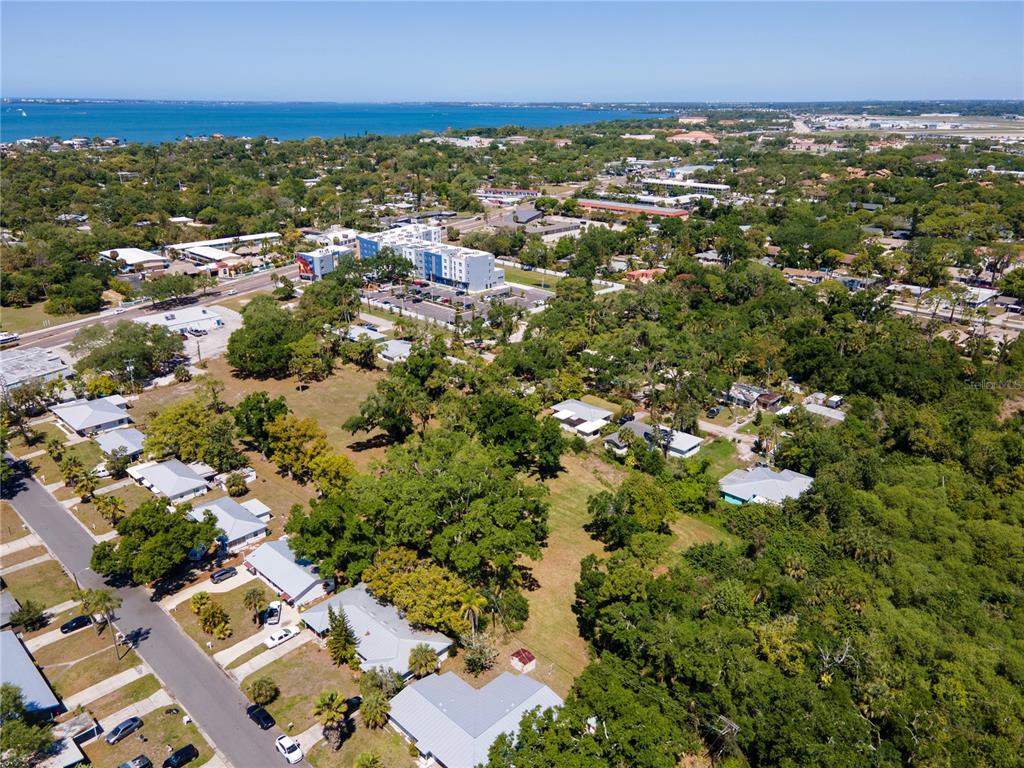 An aerial view shows a residential neighborhood with houses, trees, and a distant body of water — 4500 N TAMIAMI TRAIL, SARASOTA, FL