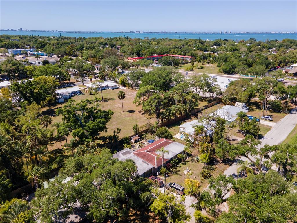 An aerial view shows a residential property with a red-roofed house surrounded by trees — 4500 N TAMIAMI TRAIL, SARASOTA, FL