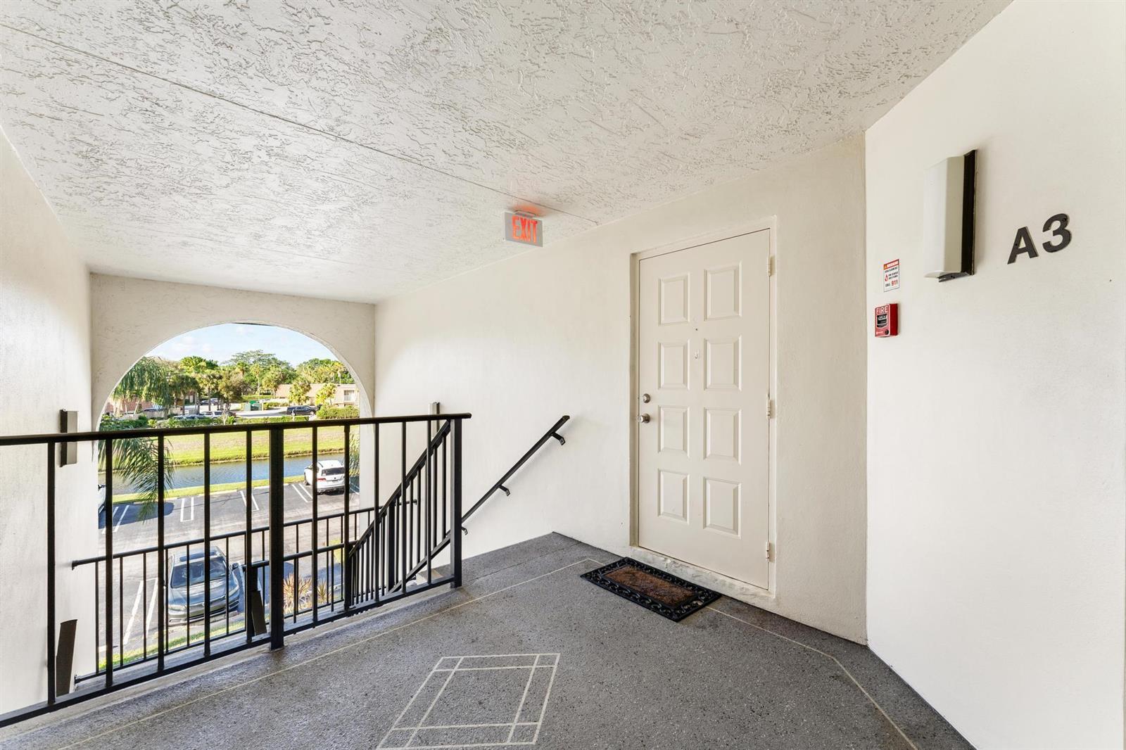 An outdoor apartment landing features a white door labeled A3, stairs, and a metal railing — 1108 Green Pine Boulevard # A3, West Palm Beach FL 33409, WEST PALM BEACH, FL