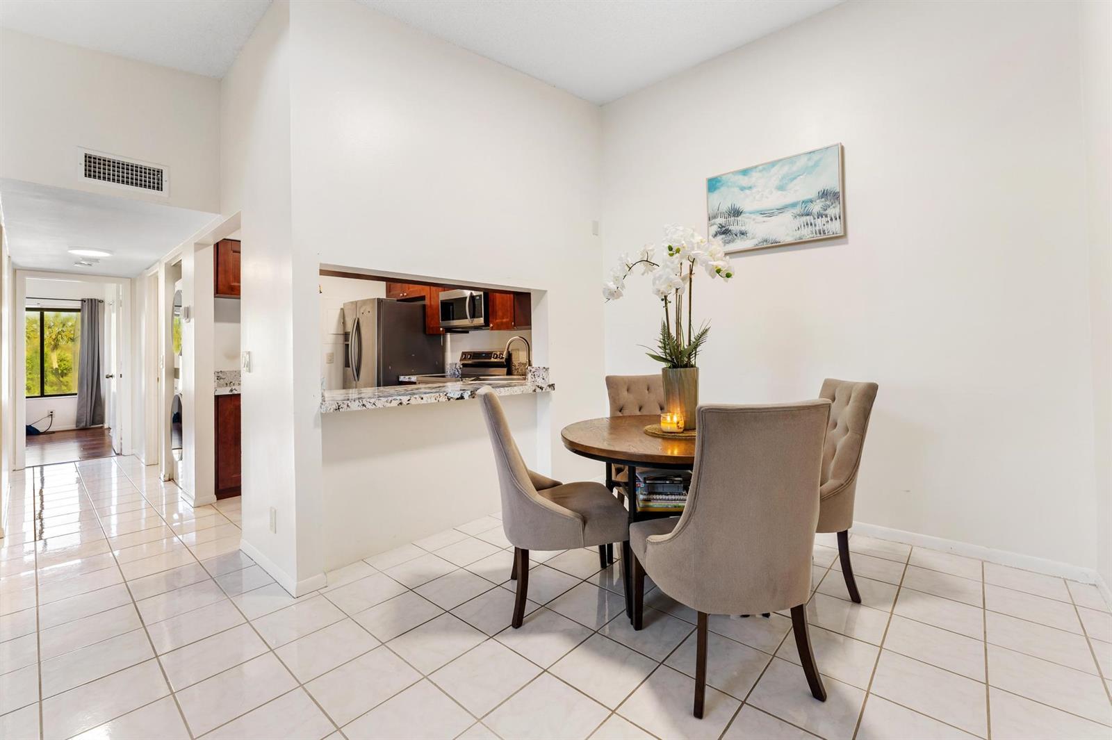 A dining area with a round table, four chairs, and a pass-through to the kitchen — 1108 Green Pine Boulevard # A3, West Palm Beach FL 33409, WEST PALM BEACH, FL