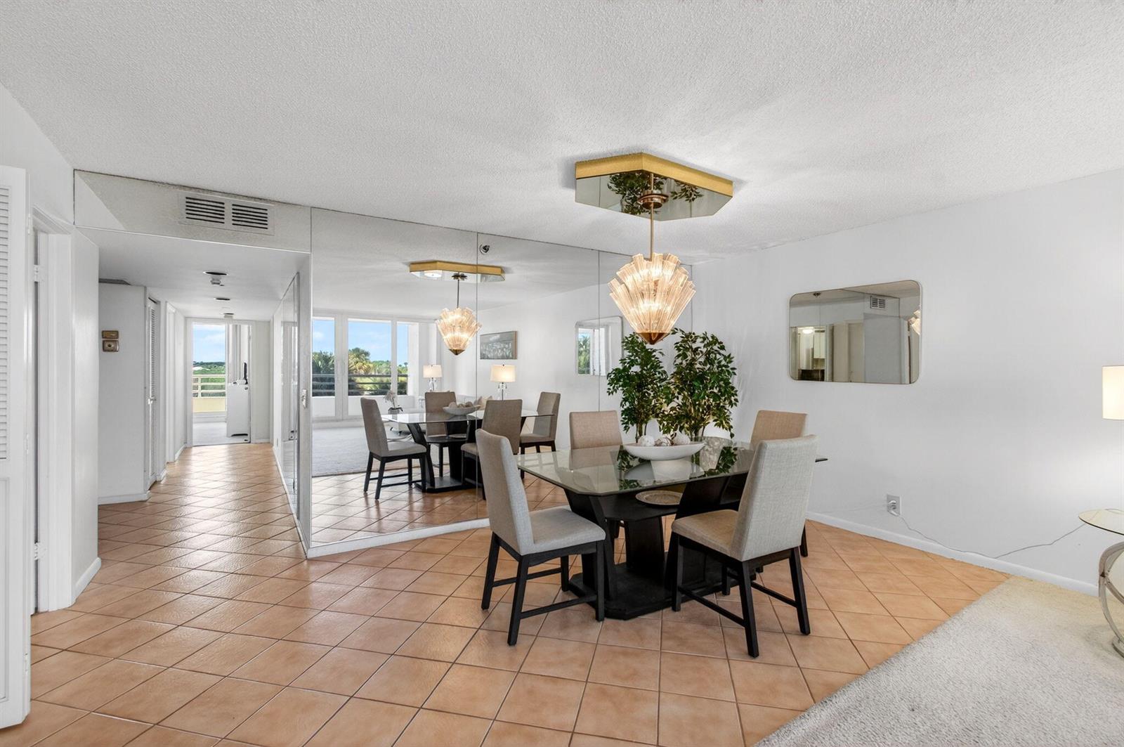 A dining room with a glass table, upholstered chairs, a mirrored wall, and tile flooring — 4201 N Ocean Boulevard # 307, Boca Raton FL 33431, BOCA RATON, FL