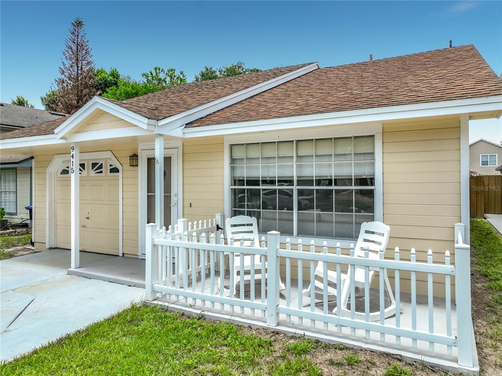 A yellow single-story house features a white picket fence, a front porch, and a garage — 9415 DANEY STREET, GOTHA, FL