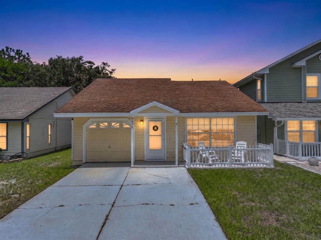A single-story yellow house with a brown roof, a garage, and a small front porch — 9415 DANEY STREET, GOTHA, FL