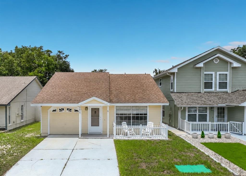 A yellow single-story house with a brown shingled roof, a garage, and a front porch — 9415 DANEY STREET, GOTHA, FL
