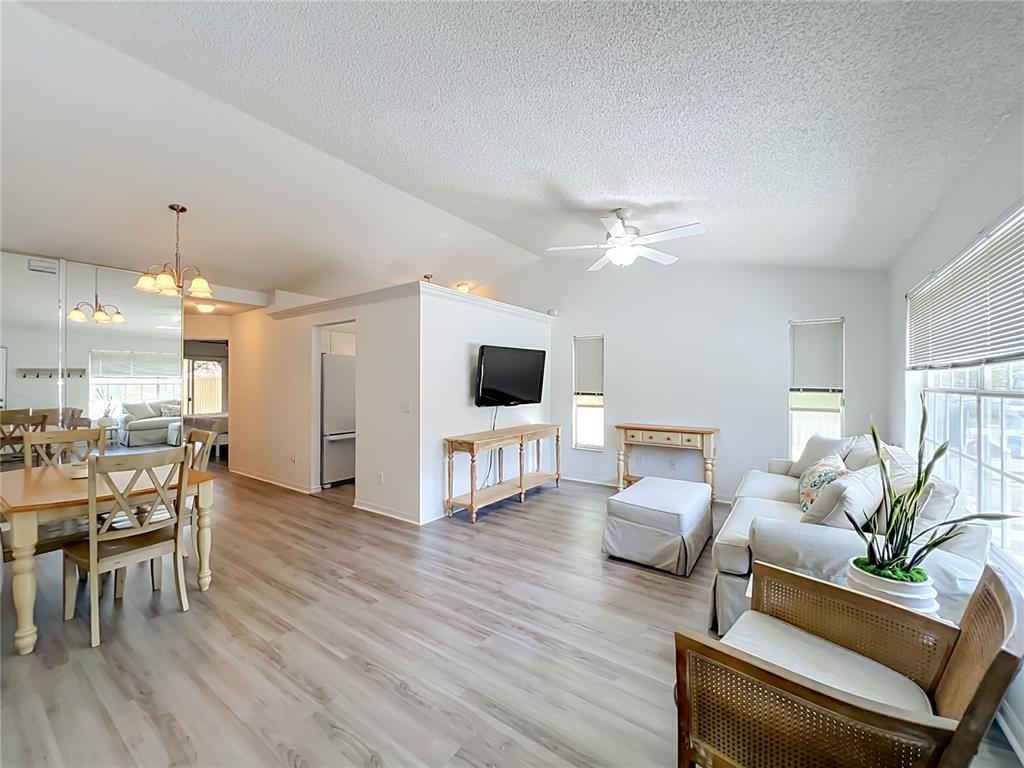A living and dining area with light wood flooring, white walls, and a ceiling fan — 9415 DANEY STREET, GOTHA, FL