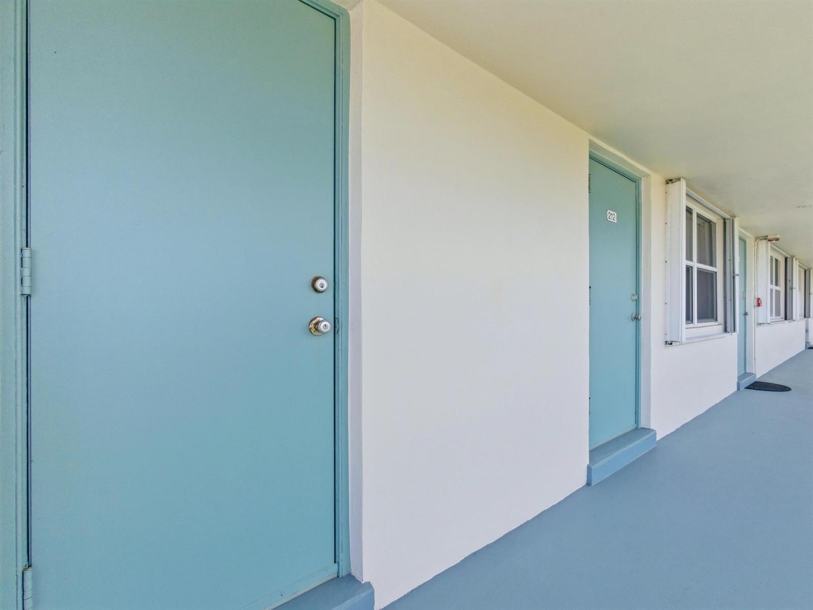 An exterior walkway features light blue doors and white walls along a motel corridor — 680 W Horizons # 212, Boynton Beach FL 33435, BOYNTON BEACH, FL