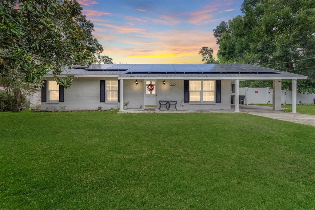 A single-story brick house with a solar panel roof and an attached carport — 37237 NICOLE AVENUE, ZEPHYRHILLS, FL