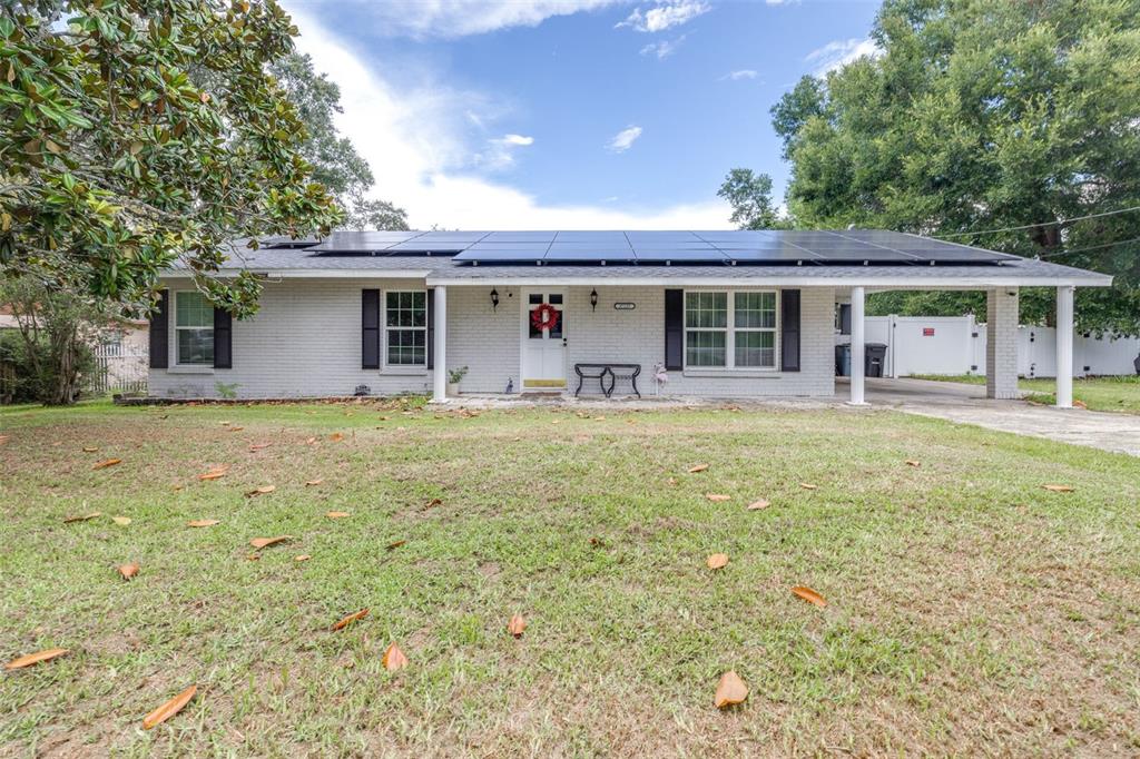 A single-story brick house with a solar panel roof and a front carport — 37237 NICOLE AVENUE, ZEPHYRHILLS, FL