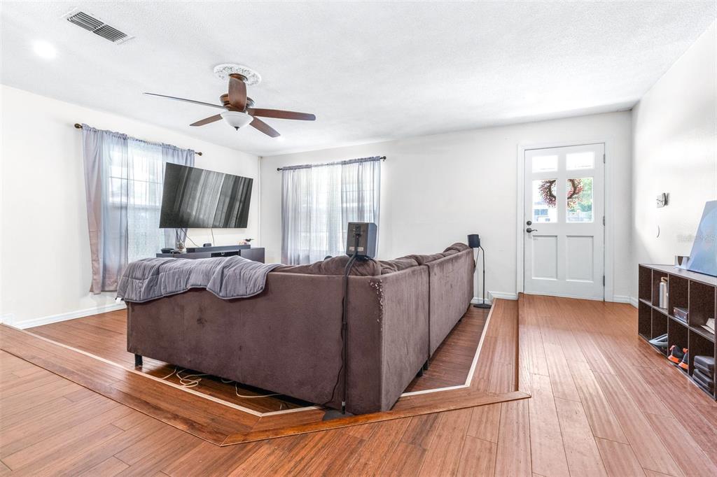 A living room features a sunken seating area with a brown sectional sofa and wood flooring — 37237 NICOLE AVENUE, ZEPHYRHILLS, FL