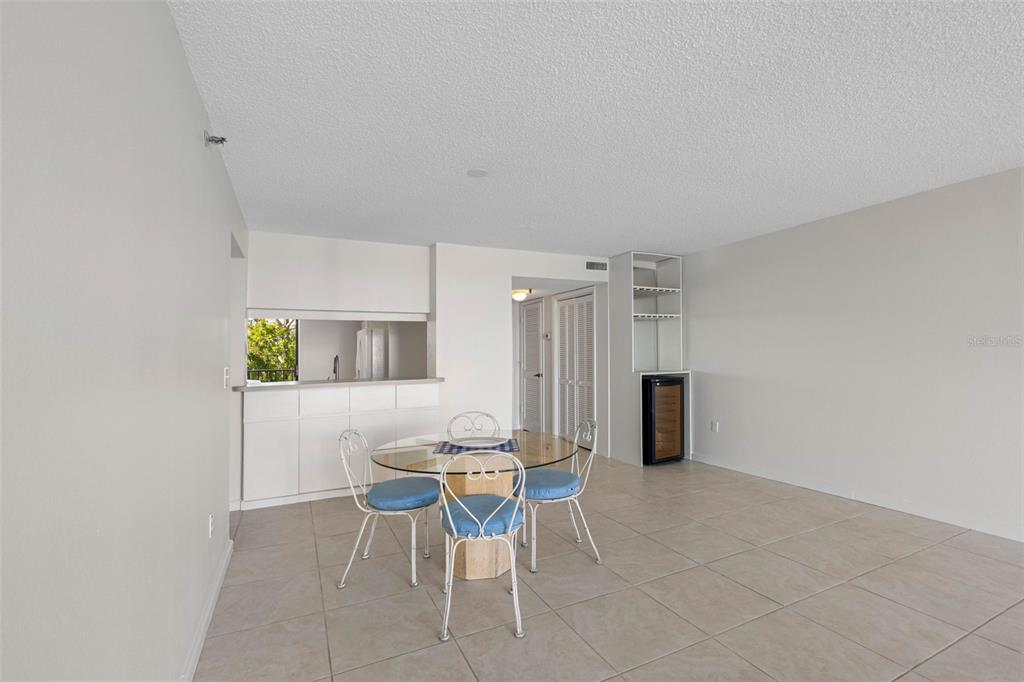 An empty living room with light tile flooring, white walls, and a sliding glass door — 19111 VISTA BAY DRIVE UNIT 204, INDIAN SHORES, FL