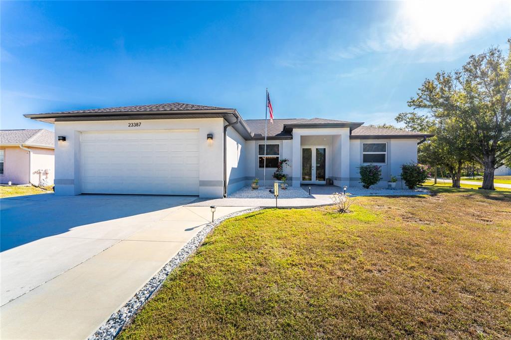 A single-story house features a white stucco exterior, a two-car garage, and a front entrance — 23387 CEDARTON AVENUE, PUNTA GORDA, FL