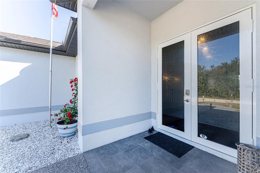 A white double door entrance with glass panels opens onto a gray tiled porch — 23387 CEDARTON AVENUE, PUNTA GORDA, FL