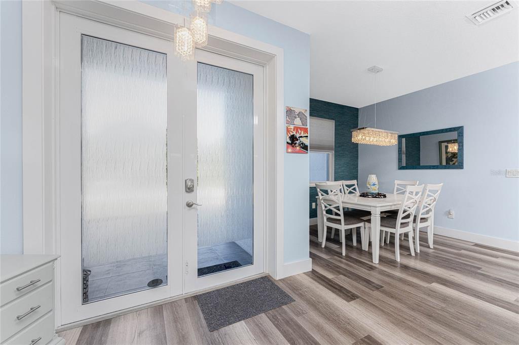 A dining area with a white table and chairs sits beside a glass-paned double door — 23387 CEDARTON AVENUE, PUNTA GORDA, FL