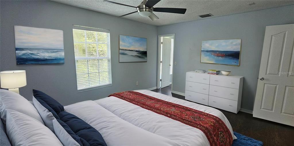 A bedroom features a bed with a red runner, white dresser, and three landscape paintings — 4337 DEERMONT CIRCLE, TAMPA, FL