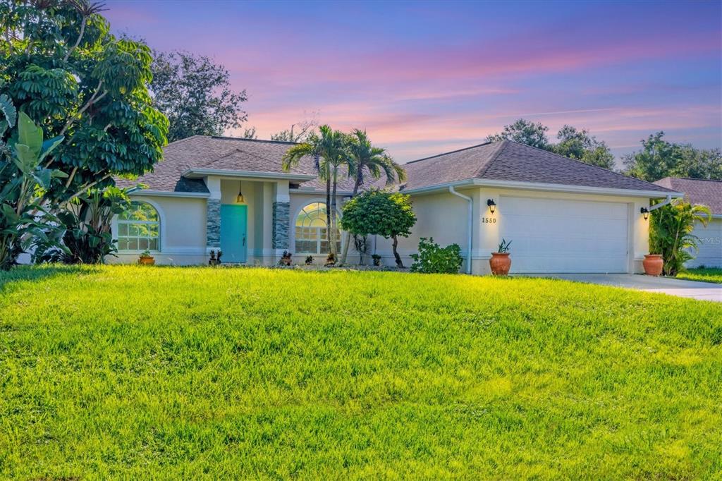 A single-story house with a turquoise front door, arched windows, and a two-car garage — 1550 S BISCAYNE DRIVE, NORTH PORT, FL