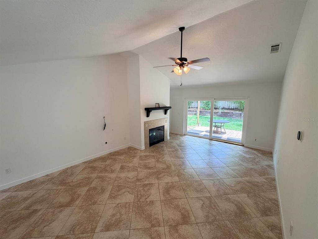 A living room features beige tile flooring, a fireplace, a ceiling fan, and sliding glass doors — 1083 BECKSTROM DR, OVIEDO, FL