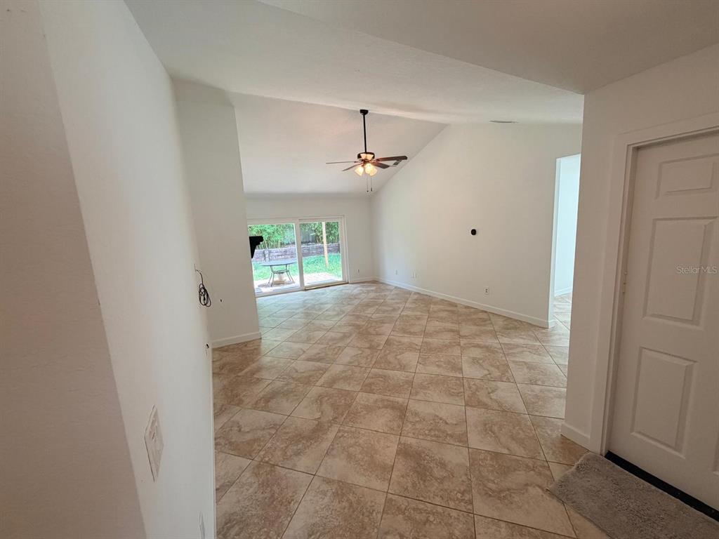 A living room with vaulted ceilings, tile flooring, and sliding glass doors leading outside — 1083 BECKSTROM DR, OVIEDO, FL