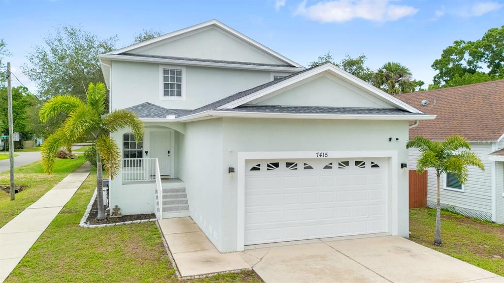 A two-story house with a light green exterior, a front garage, and a palm tree — 7415 S ELLIOTT STREET, TAMPA, FL